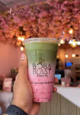 A creator visits Boba Blast in East London to review their matcha lattes, showcasing the shop's cherry blossom decor, the menu, and the preparation of various layered matcha drinks.