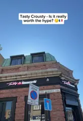 A vlog-style review of the London branch of Tasty Crousty, featuring the creator's first impressions of the venue, the kiosk ordering process, and a taste test of their chicken tenders, rice box, and Oreo milkshake in a nearby park.