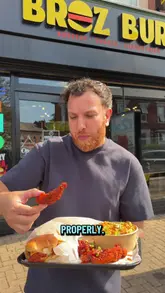 A creator performs a spontaneous 'random' review of a local takeaway shop called Broz Burg in Birmingham. The video features the creator walking to the venue, interacting with staff, and reviewing the food (burgers, loaded fries, and chicken tenders) outside.