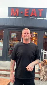 A creator visits M.EAT Smokehouse in Sheffield, reviewing their 'Carnivore Plate' which includes brisket, lamb, burgers, and mac and cheese. The video captures the dining experience from arrival to takeaway, highlighting the quality of the food and the friendly service.