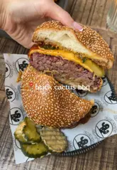 A short, punchy video showcasing a burger at Black Cactus BBQ, featuring close-up shots of the burger being held and cut in half to reveal the inside.