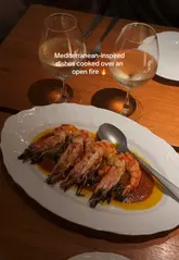 A visually appealing montage showcasing a dinner experience at Firebird in Soho, highlighting the open-fire cooking, cocktails, and various Mediterranean-inspired dishes.
